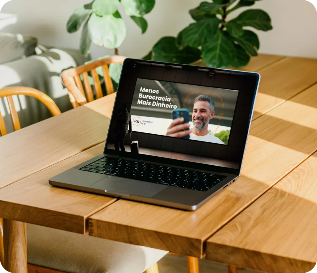 Laptop com tela exibindo o título "Menos Burocracia Mais Dinheiro" e um homem sorrindo.